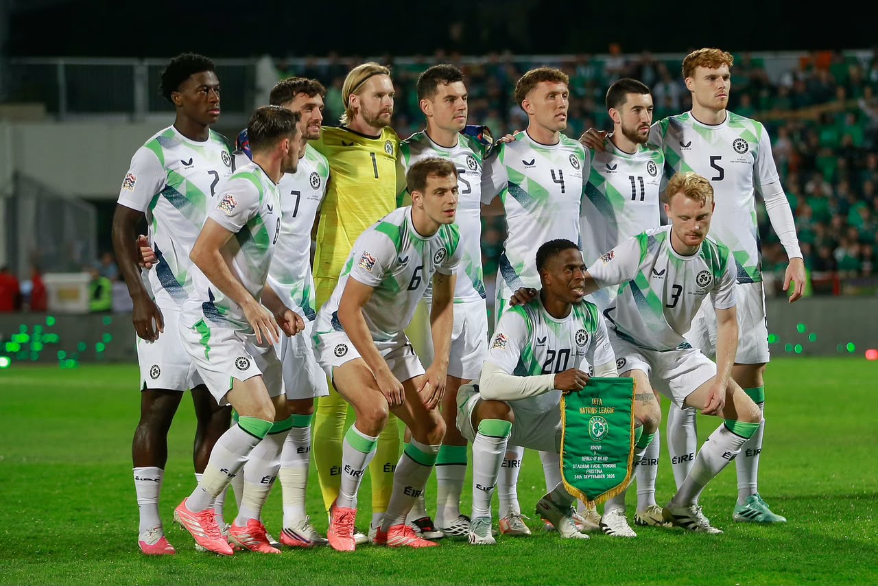 Republic of Ireland football players pose for a team photograph before their international match, wearing white and green kits with their goalkeeper in yellow.