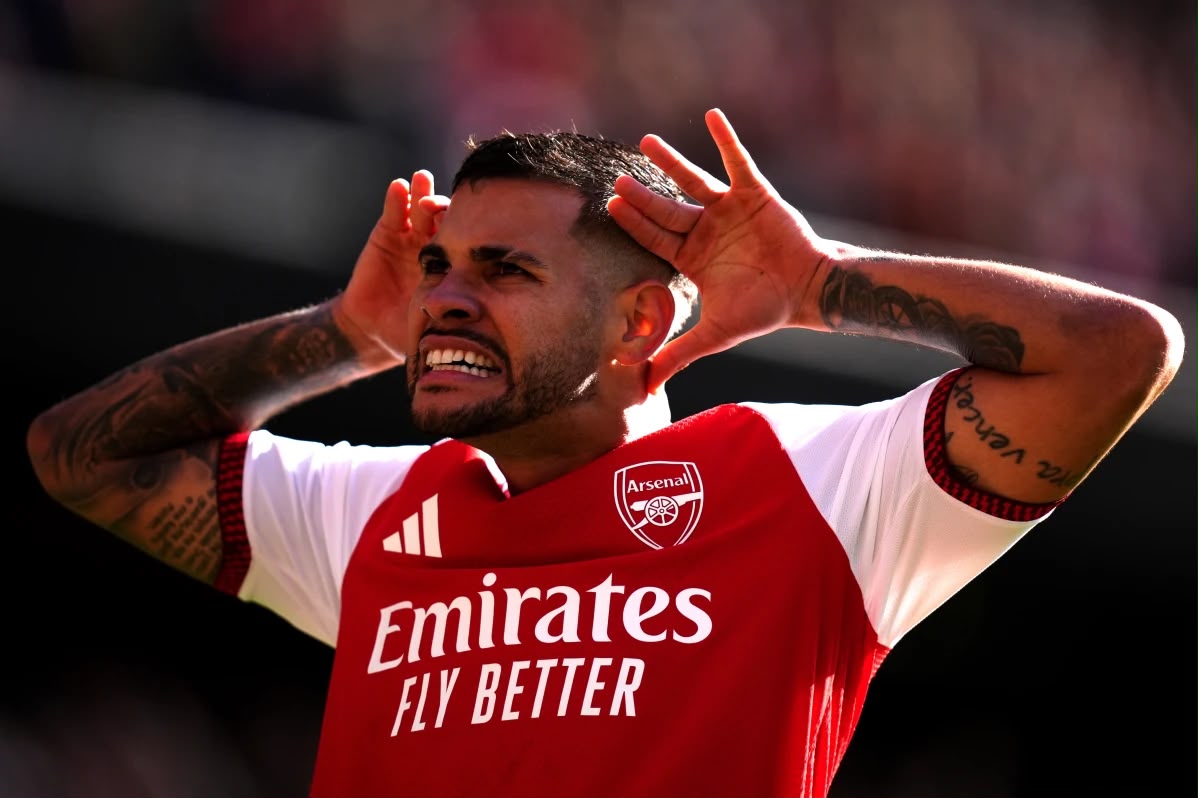 Close-up shot of Arsenal player Bruno Guimarães holding his hands up behind his ears with a fierce expression on his face during a match celebration.